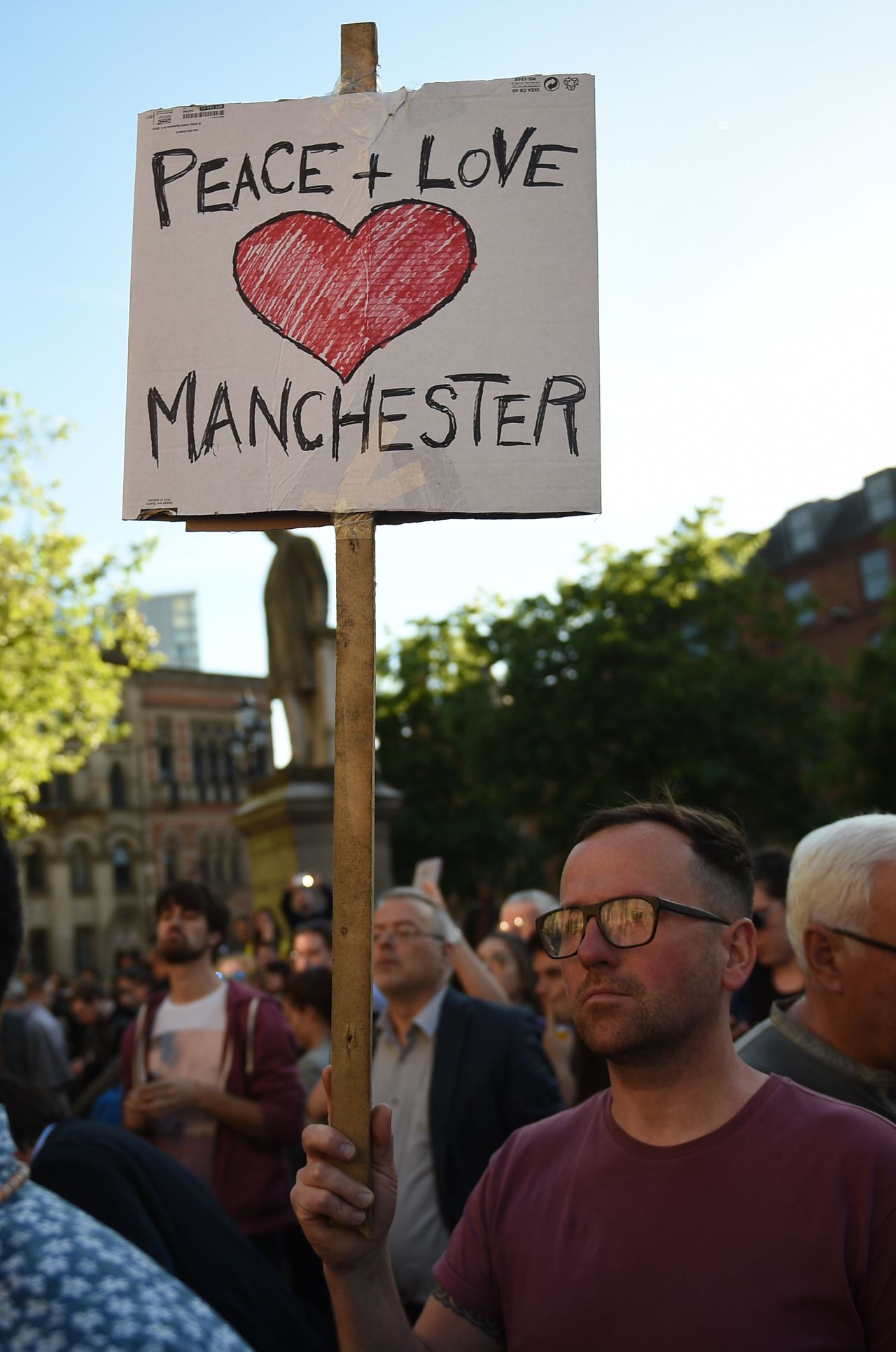 A man holds a banner reading 'Peace and Love Manchester' during a vigil in Albert Square in Manchester last year.