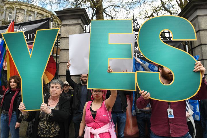 'Yes' vote campaigners cover anti-abortion group's graphic images related to pregnancy and abortion with Irish and rainbow flags outside Irish Parliament 