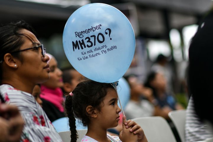 A young girl holds a balloon with a message during a memorial event for the missing Malaysia Airlines flight MH370.