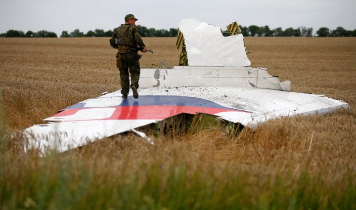 an armed pro-russian separatist stands on part of the wreckage