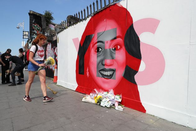 A woman lays flowers next to a mural of Savita Halappanavar in Dublin, as Ireland went to the polls. Savita lost her life after a miscarriage in a Galway hospital.