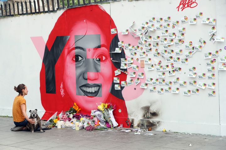 A woman kneels infront of a mural of Savita Halappanavar in Dublin