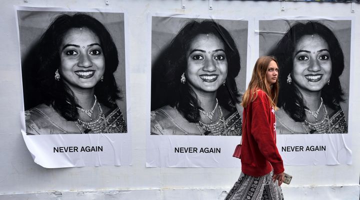 A young woman walks past art work featuring Savita Halappanavar 
