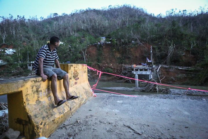 A man sits on the edge of a broken bridge spanning the Vivi River on Oct. 20, 2017 in Utuado, Puerto Rico.