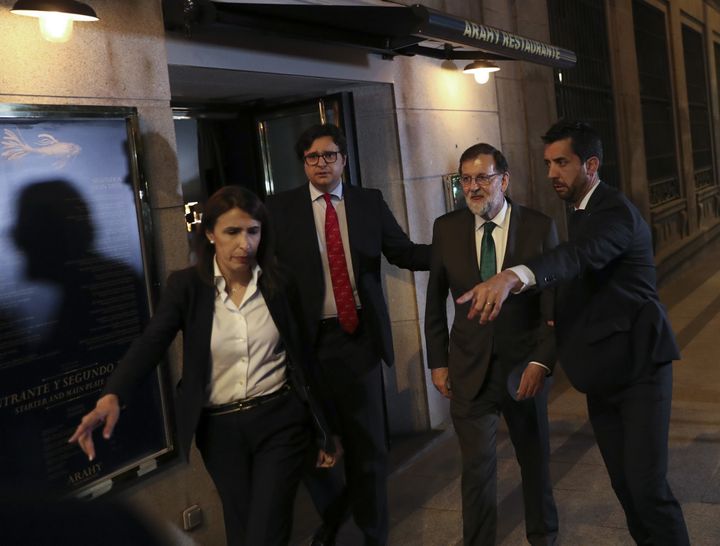 Spain's former Prime Minister Mariano Rajoy is led to his car just after 10pm local time after spending more than right hours in the Arahy restaurant in central Madrid