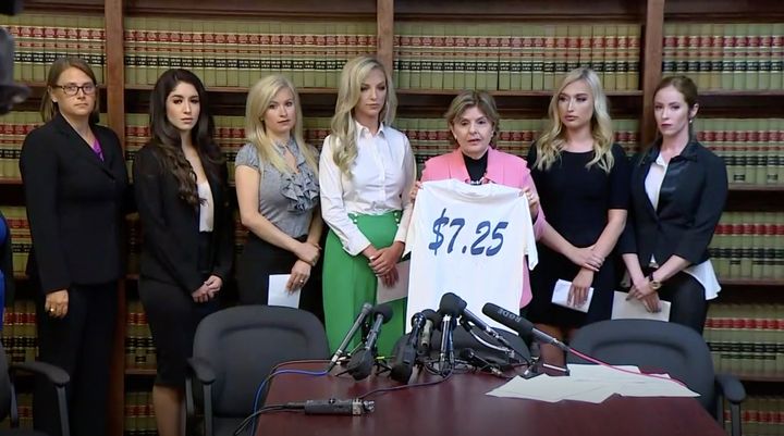 Gloria Allred, holding a T-shirt featuring the federal minimum wage, is flanked by five former Texans cheerleaders who are suing their former employer. They are joined by Kim Spurlock, far left, who will represent them in the case.