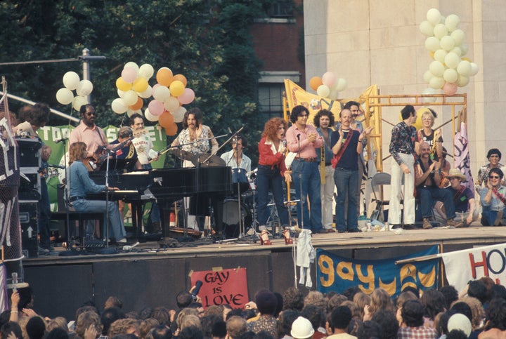 Barry Manilow (seated at piano) and Bette Midler (at center, in red) at a Gay Liberation rally at Washington Square Park on June 24, 1973, in Greenwich Village, New York City. 