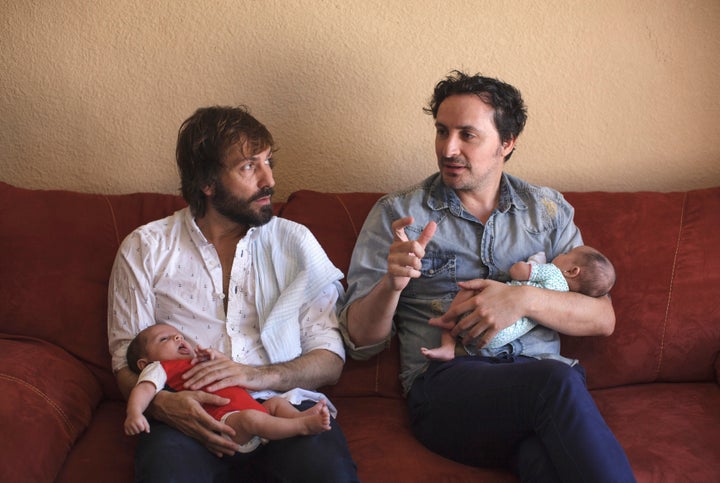 Luis Delgado, left, and Antonio Ferndandez, right, hold their twins Marco and Olivia in Cancun, Mexico, on Feb. 24, 2015