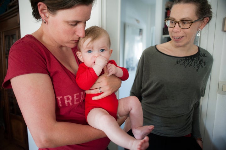 Two mothers pose with their five-month-old baby in France.