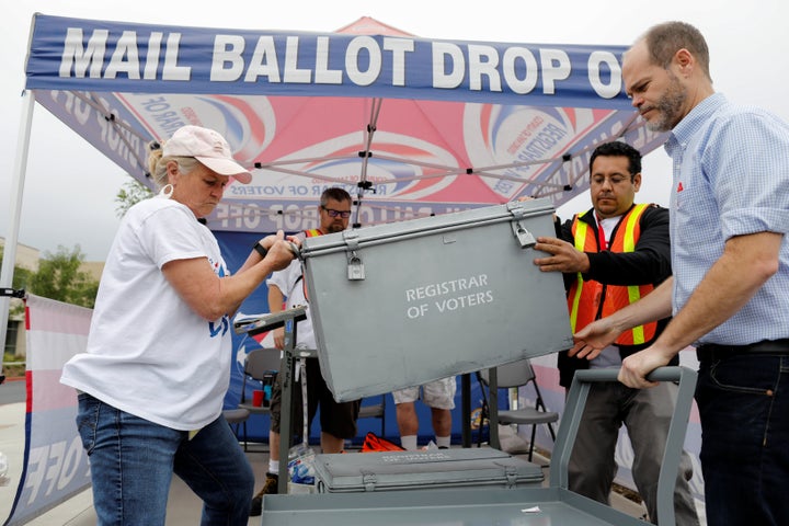 Election workers take away a ballot box full of votes at a drive-through ballot drop-off site in San Diego on Tuesday.