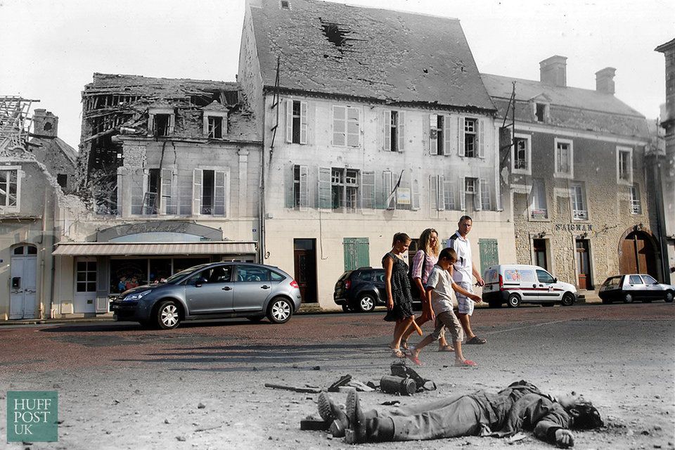 Tourists walk by where the body of a dead German soldier that once lay in the main square of Place Du Marche in Trevieres after the town was taken by US troops who landed at nearby Omaha Beach in 1944.