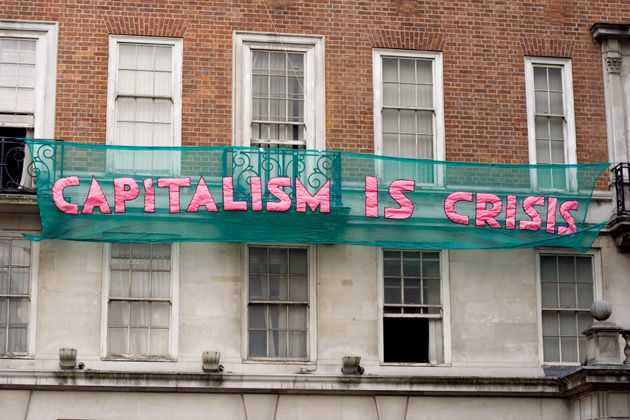 Protestors hang anti-capitalism slogans on buildings on Clarges Street in London during the demonstrations against public sector funding cuts in March 2011