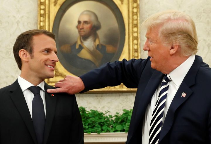 Trump brushes dandruff off French President Emmanuel Macron's jacket during their meeting in the Oval Office in Washington in April 