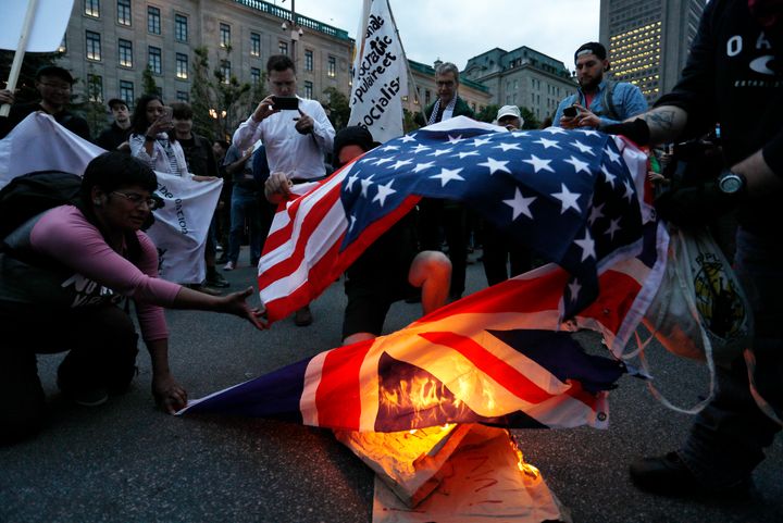 Demonstrators burn US and British flags at a protest march ahead of the G7 summit on June 7