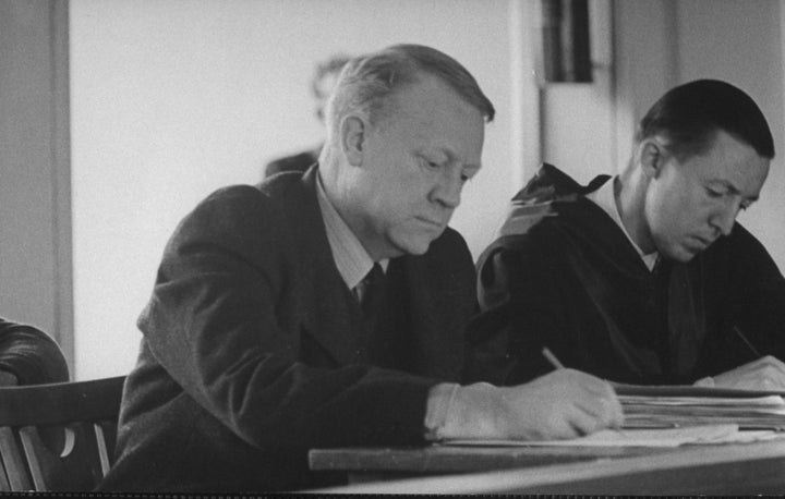 Vidkun Quisling (left) jotting down a note during trial.