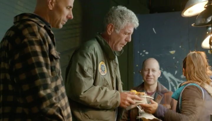 Anthony Bourdain with a plate of morcilla and potato cakes in Corona, Queens.