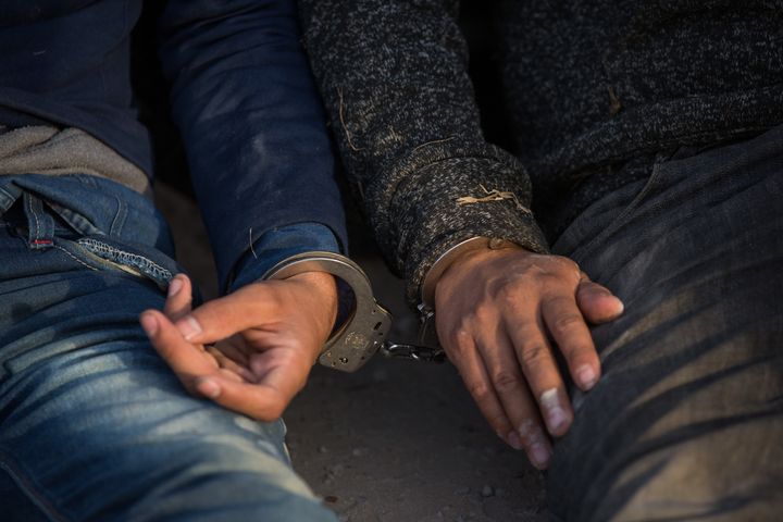 Two immigrants apprehended by Border Patrol wait to be transported to a central processing center after crossing the border from Mexico into the U.S. in March.