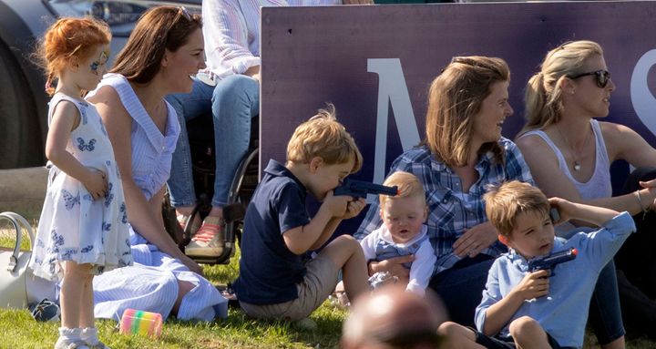 Prince George plays with a toy gun as he sits with his mother, the Duchess of Cambridge.