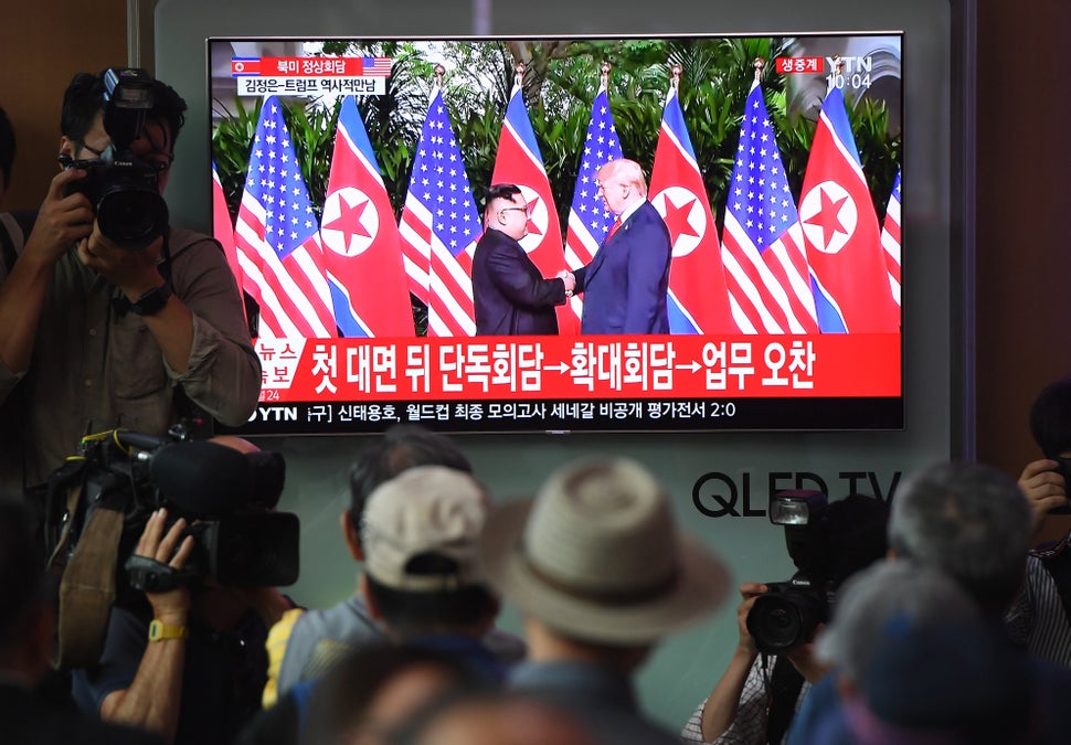 People watch live footage of the handshake between Kim and Trump.