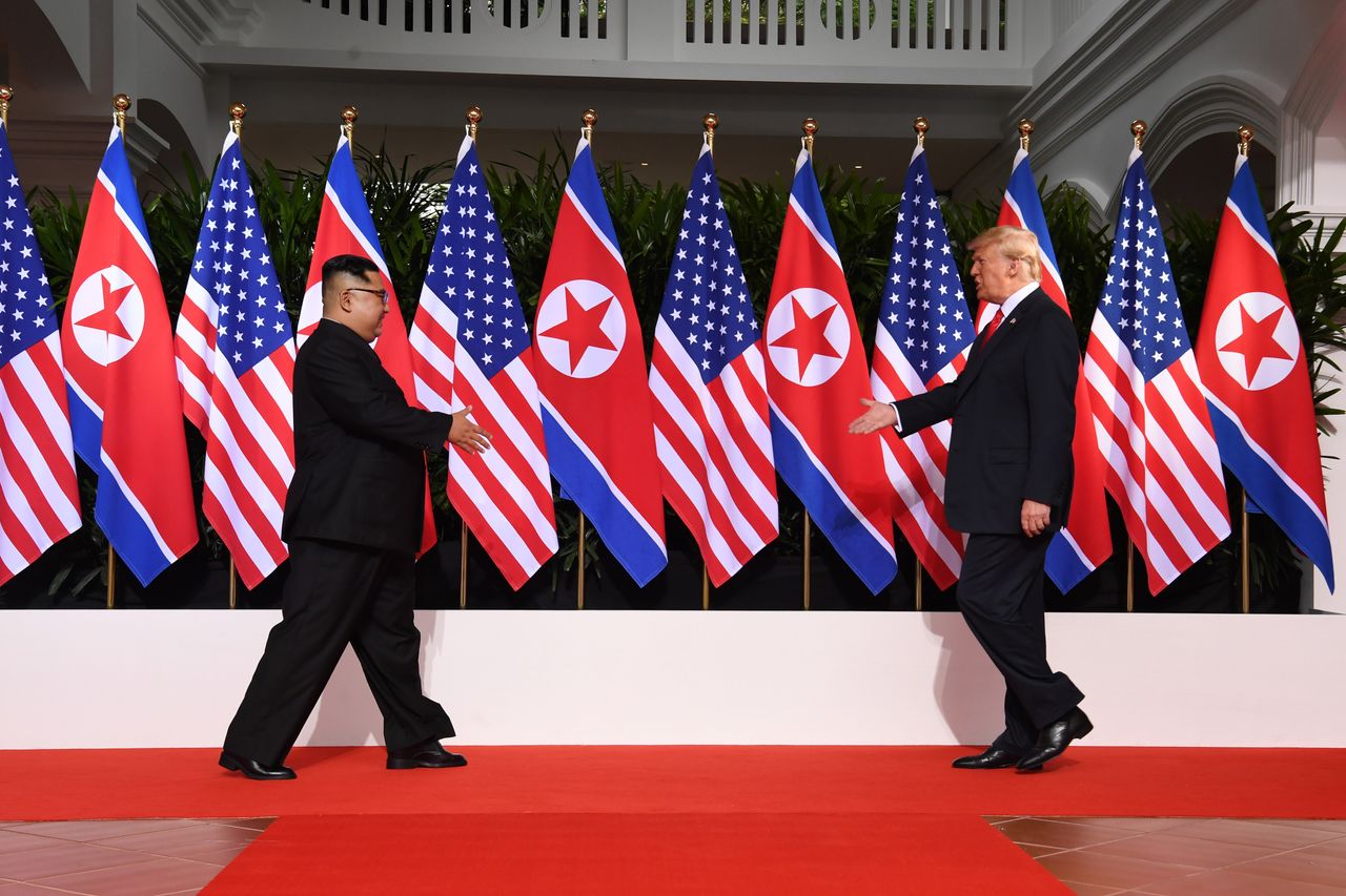 North Korean leader Kim Jong Un and U.S. President Donald Trump extend their hands as they meet in Singapore on June 12, 2018.