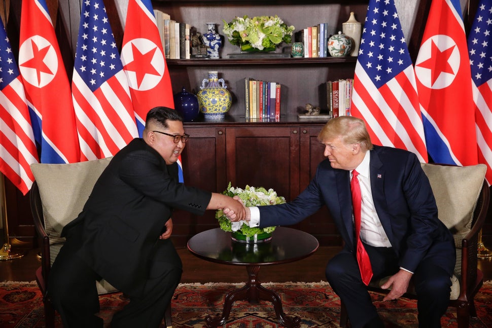 The two leaders pose for a photo op, flanked by American and North Korean flags.