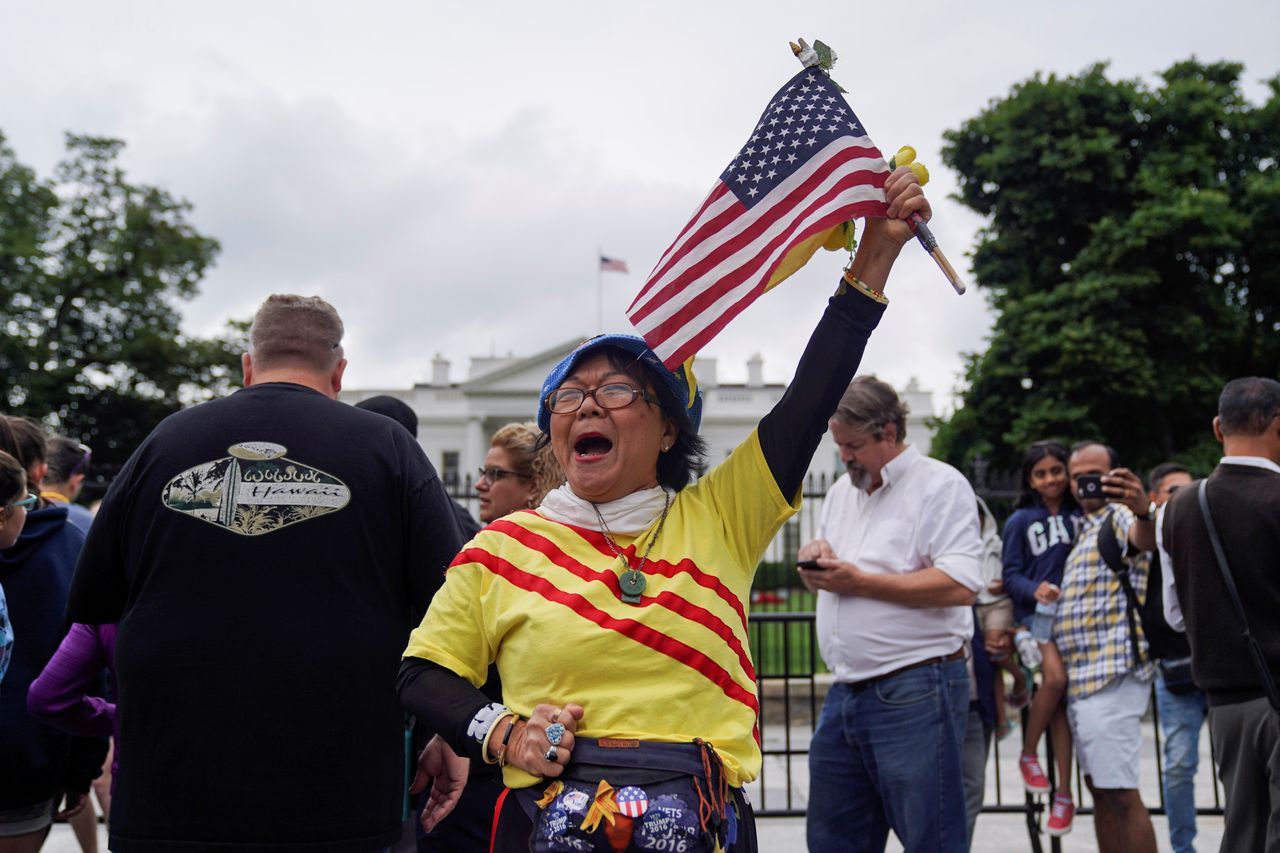 Meanwhile back in Washington DC, Victoria Kim, a Vietnamese Trump supporter from California raises an American flag during a vigil outside the White House to celebrate the summit 