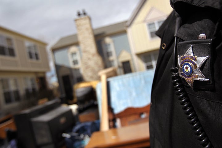 A sheriff's deputy looks over a family's belongings piled in the front yard of an apartment after they were removed by an evi