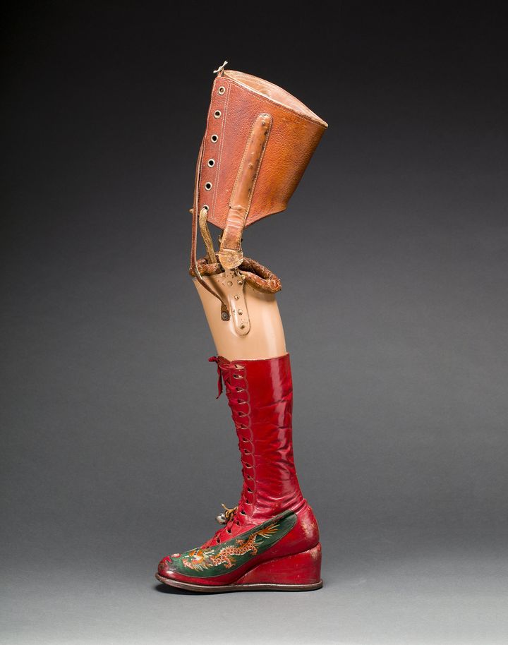 Prosthetic leg with leather boot. Appliquéd silk with embroidered Chinese motifs.