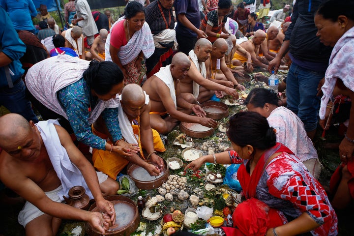 People perform rituals to honor their deceased fathers at a temple on the Bagmati River in Gokarna, Nepal.