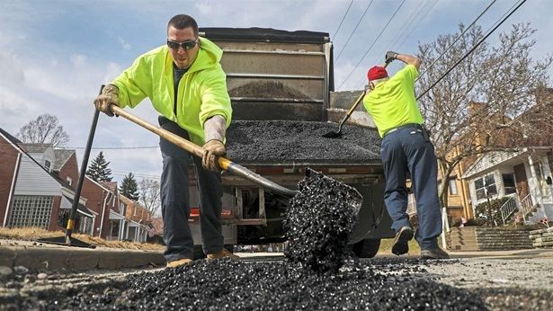City workers patch Pittsburgh potholes. Some cities are using technology to track potholes.