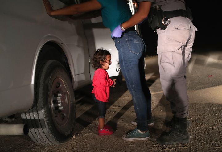 A Honduran girl cries as her mother is stopped and searched on the border