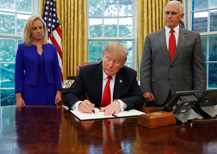 President Donald Trump signs an executive order on immigration policy on June 20, 2018, as Department of Homeland Security Secretary Kirstjen Nielsen and Vice President Mike Pence look on.