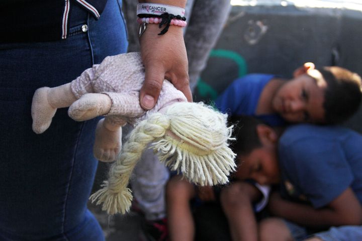 A Mexican woman holds a doll next to children at the Paso Del Norte Port of Entry at the U.S.-Mexico border on June 20.