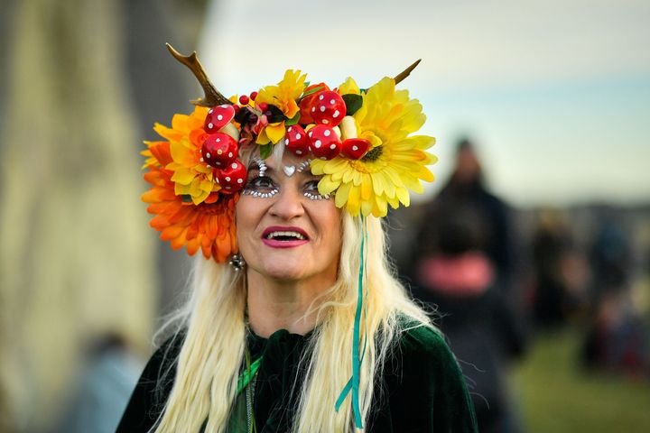 A woman wears a colourful headdress as she celebrates the dawn of the longest day in the UK 
