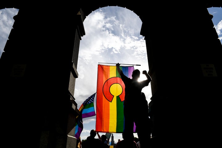 A protester holds a Colorado pride flag during a rally at the Colorado State Capitol after the Supreme Court ruled in favor of Jack Phillips, owner of Masterpiece Cakeshop.