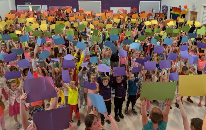 Children at Downfield Primary School hold up coloured card to make a 400-person rainbow flag.