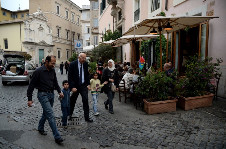 A family of Syrian refugees that Pope Francis brought back with him from the Greek island of Lesbos walks with a Catholic charity worker on April 18, 2016, in Rome.