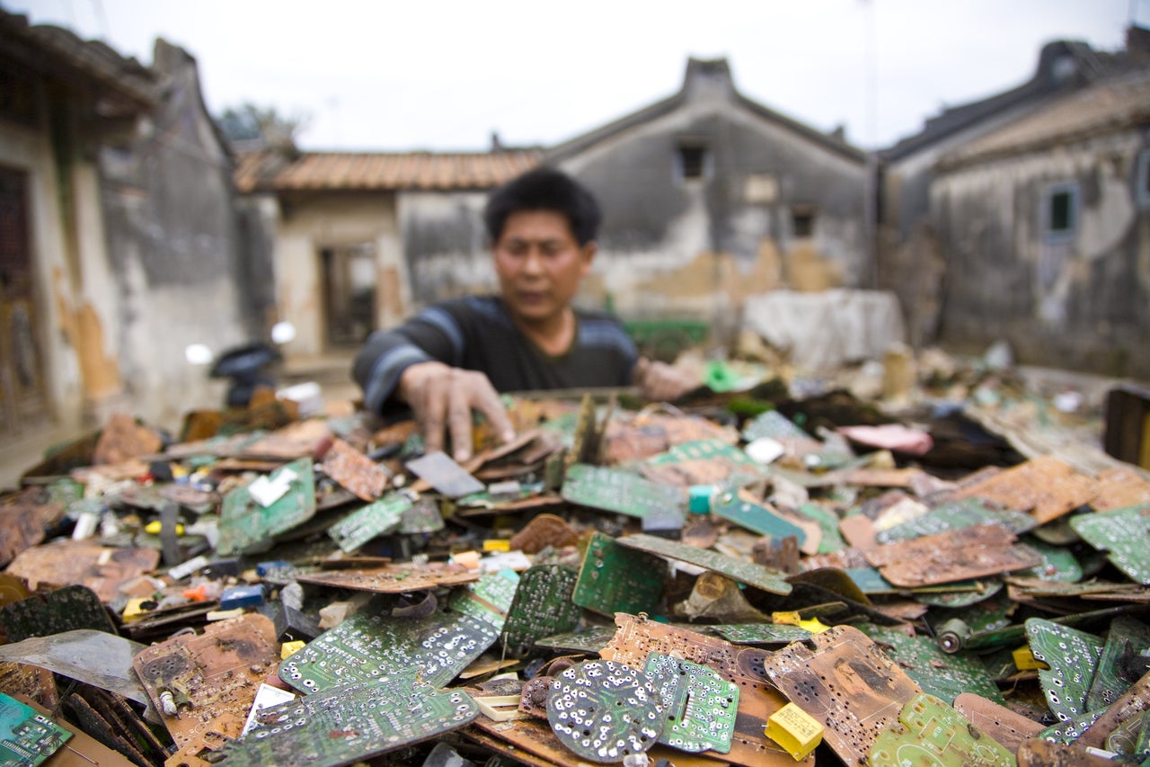 A worker in China sorts through stripped computer boards.