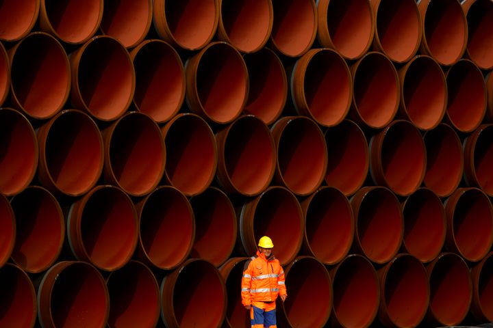 A worker stands in front of pipes which lie stacked at the Nord Stream 2 facility on Ruegen Island, Germany, in October 2017.