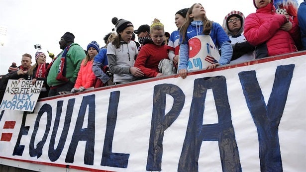 Fans protest for higher wages for the U.S. women’s soccer players at a match against Colombia in East Hartford, Connecticut. The women’s team has won three World Cups but its players are paid significantly less than the U.S. men. To help close the gender pay gap, some cities and states are barring employers from asking new hires about their current salary.