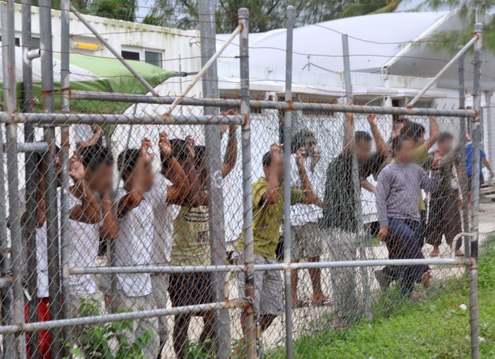 Asylum-seekers look through a fence at the Manus Island detention center in Papua New Guinea on March 21, 2014.