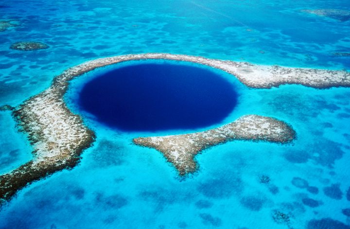 Belize's Great Blue Hole lies within the region's Belize Barrier Reef System, a UNESCO World Heritage Site.