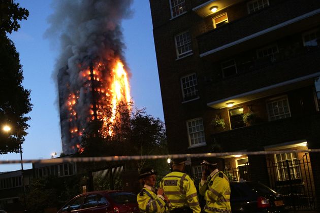 Police officers at a cordon on June 14 as the Grenfell Tower fire takes hold