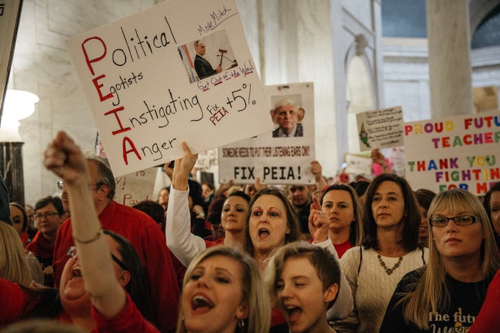 Striking school workers hold signs and chant inside the West Virginia Capitol in Charleston on March 2.