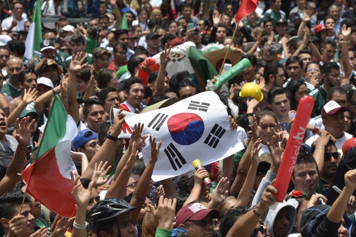 A football fan holds a flag of South Korea as thousands watch the World Cup match between Mexico and Sweden on a screen in Me
