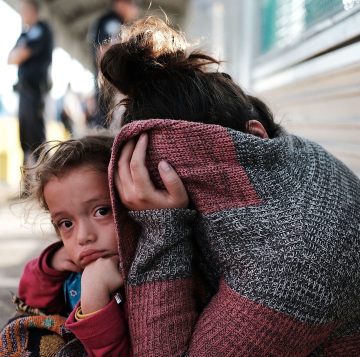 A Honduran child and her mother, fleeing poverty and violence in their home country, wait along the border bridge after being