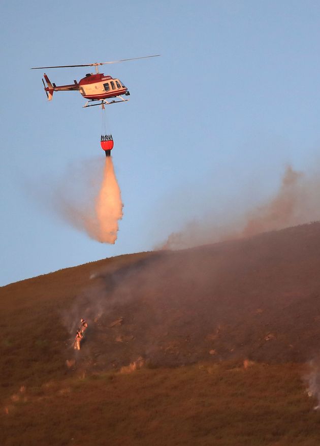 A helicopter drops water on the fire which could continue to burn for weeks 