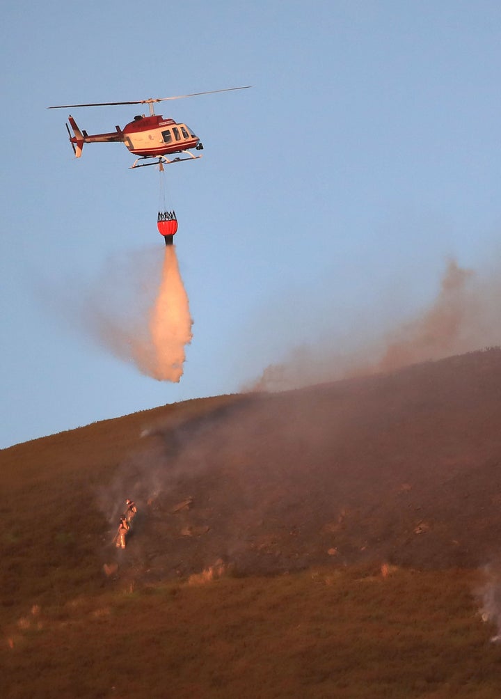 A helicopter drops water on the fire which could continue to burn for weeks 