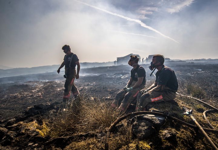 Firefighters take a rest after battling the fire that has raged since Sunday