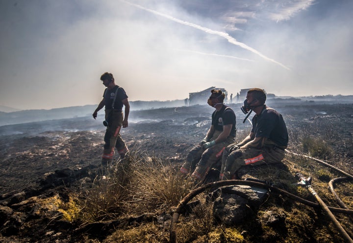 Firefighters take a rest after battling the fire that has raged since Sunday